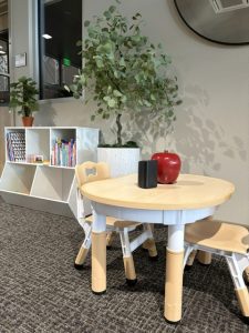 image of a small table with two chairs and a bookcase with books and toys.