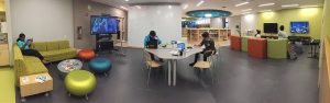 Monroe Public Library Teen Space with flexible furniture, gaming TV, craft table and teens using the library space.