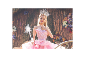 Glinda the Good Witch from Wicked is pictured with a hand over her chest. 