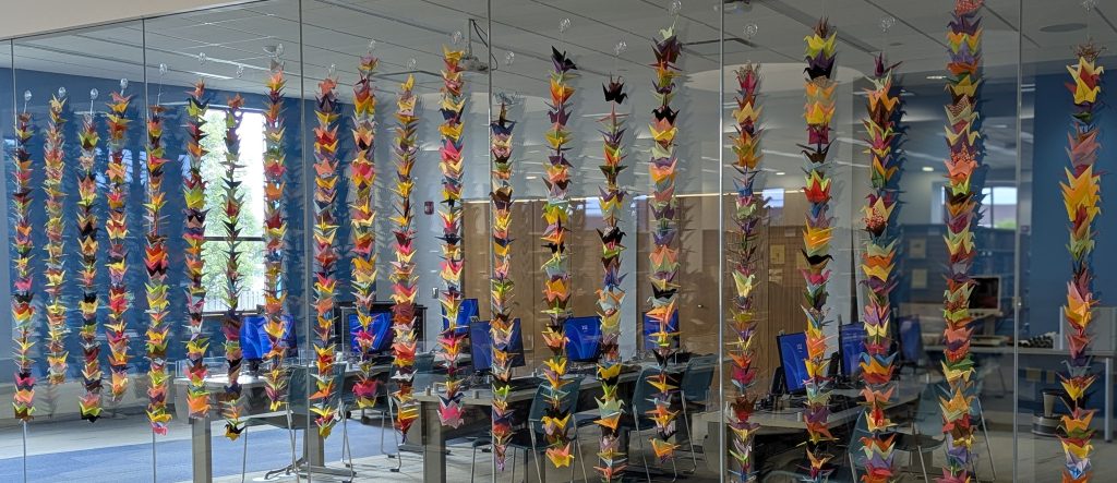1300 hanging paper cranes in front of a glass window. 