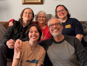 Photo of my family. In the back row: Colin, my mom, and me. In the front row is Mikko and my husband Sean.