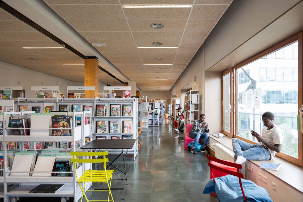 Library users seating along windows using mobile devices