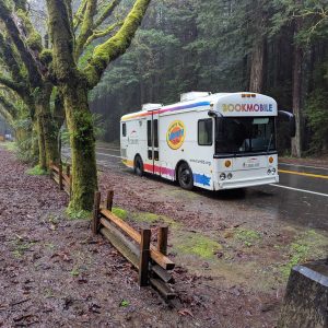 Photograph of a bookmobile parked on the side of a remote, rainy road.