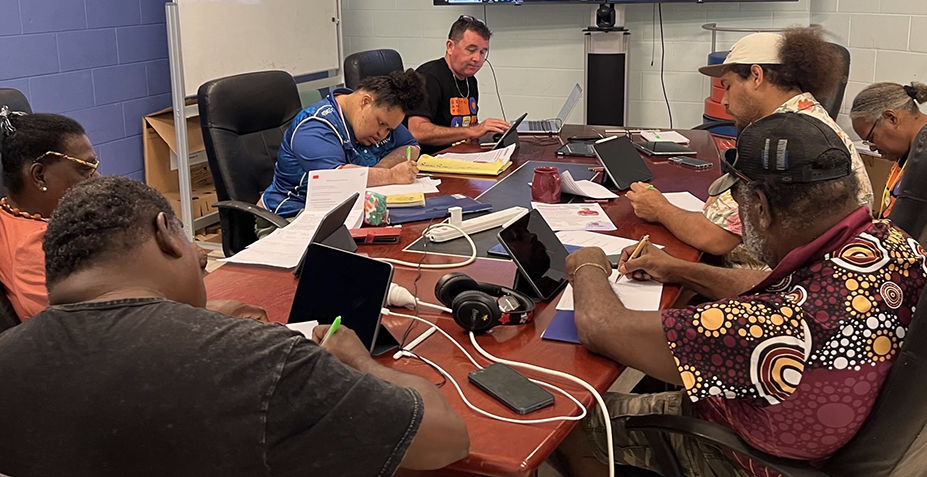 A group of people working on projects at a large table.