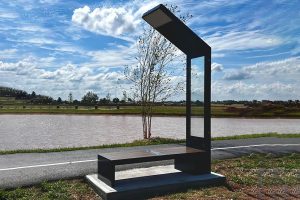 A public bench with one side going up to a solar panel.