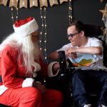 Santa talks with a kid in a wheelchair.
