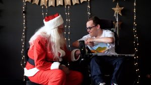 Santa talks with a kid in a wheelchair.