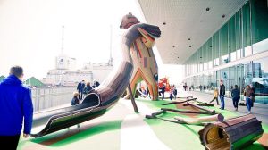 Giant wooden bear holding a slide outside a library