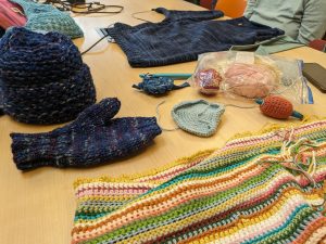 A table decked with crocheted and knitted items from a library fiber arts club.