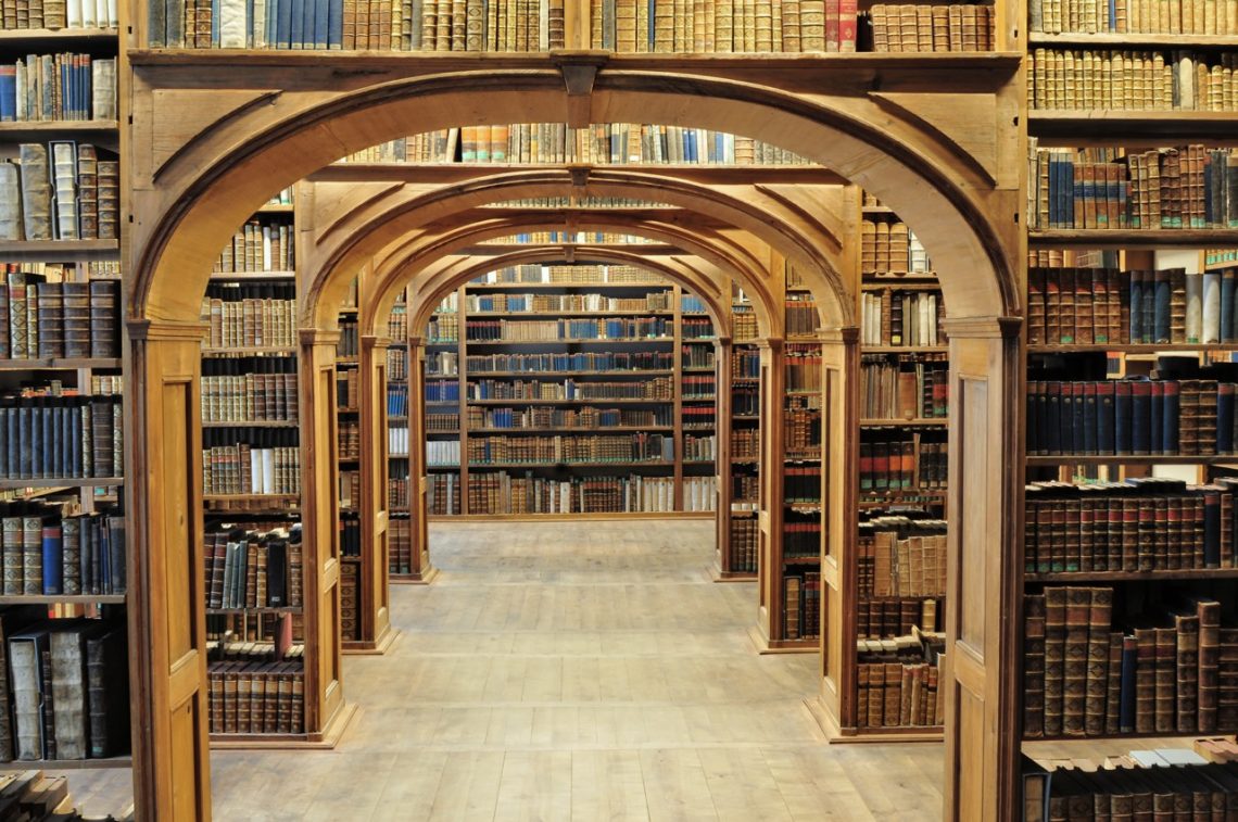 Arched wooden library stacks filled with antique books.