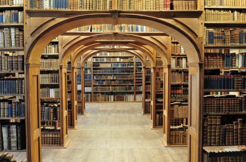 Arched wooden library stacks filled with antique books.