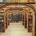 Arched wooden library stacks filled with antique books.