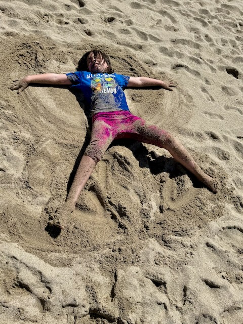 Girl on beach making a sand angel