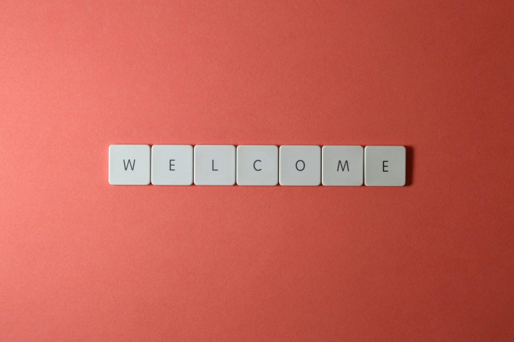 The word "welcome" is spelled out in tan tiles on a red background.